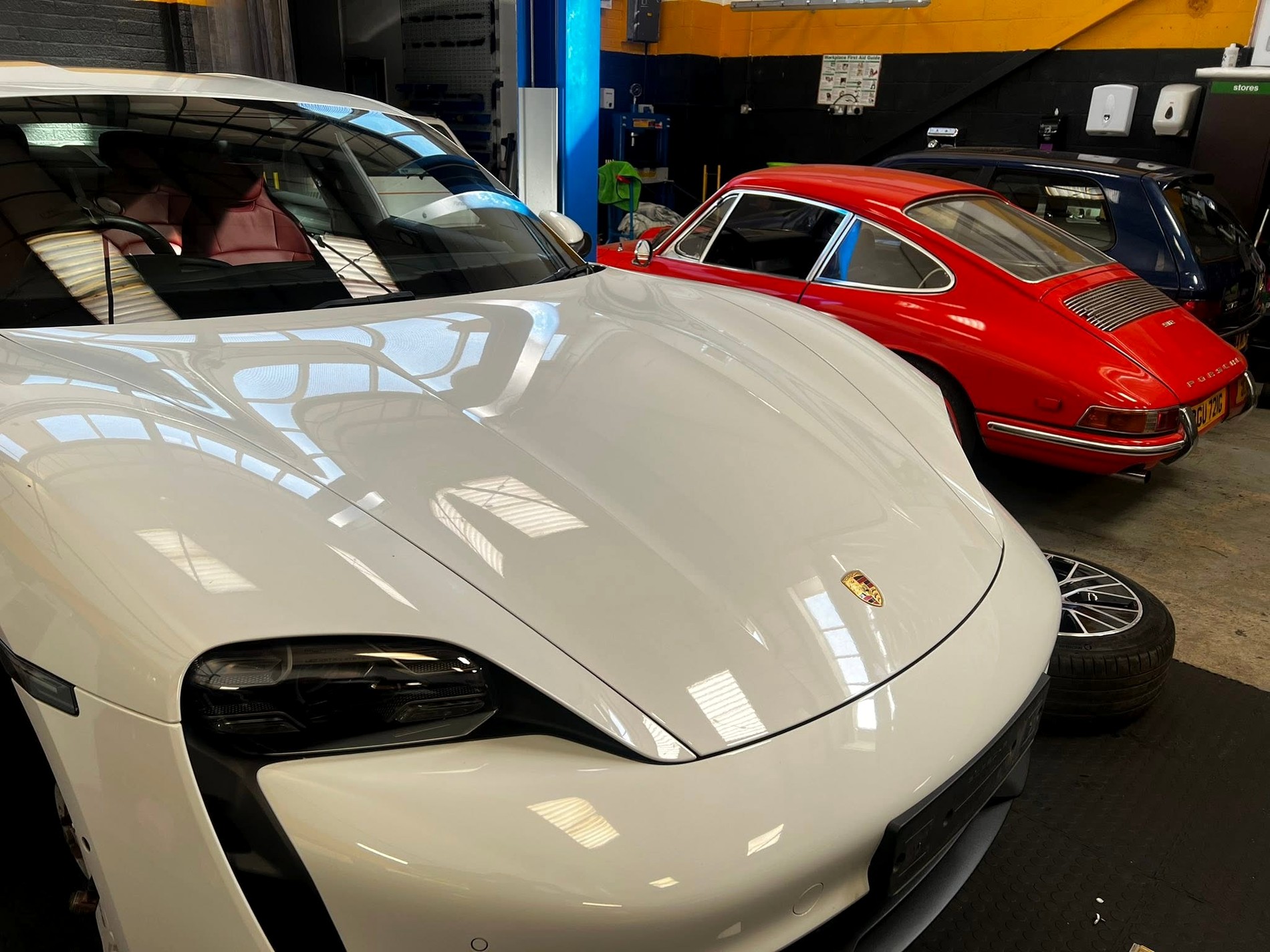 Modern Porsche Taycan with classic Porsche 911 in SG workshop